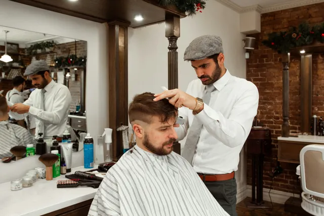 Barbiere sistema i capelli di un cliente in poltrona con il pettine